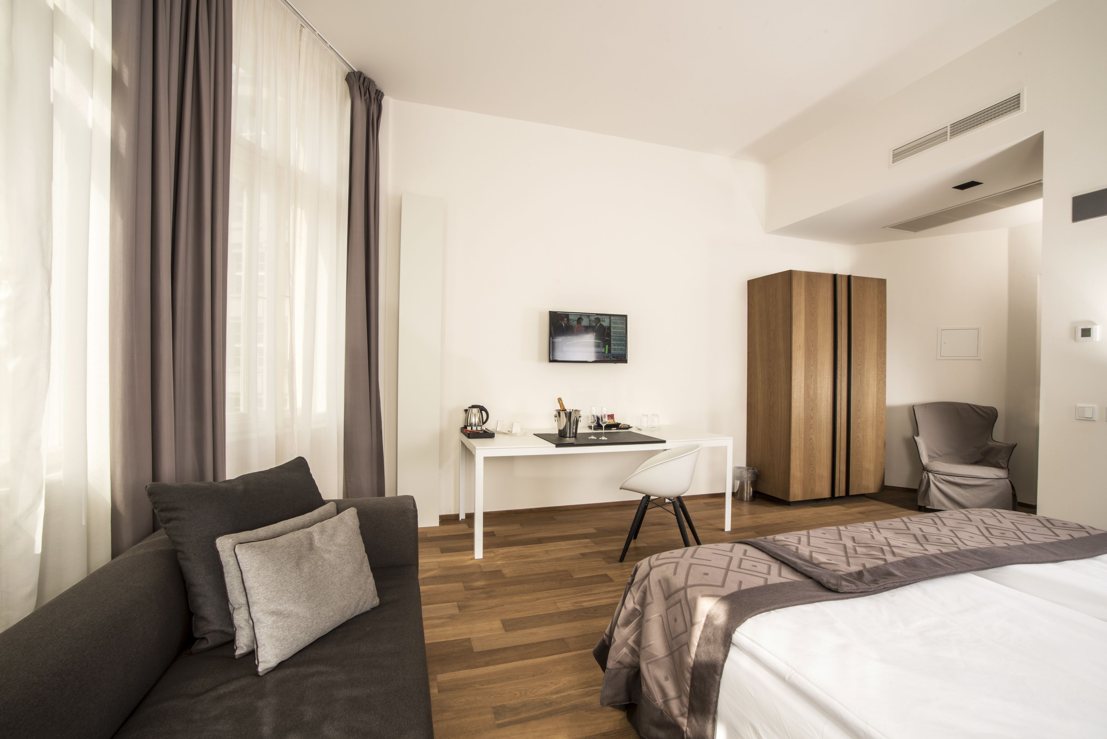 Una habitación de hotel moderna con sofá, cama, escritorio y armario.