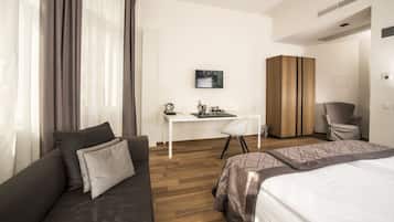 Una habitación de hotel moderna con sofá, cama, escritorio y armario.