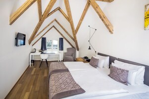 Een slaapkamer met een groot bed, een bureau en een stoel.