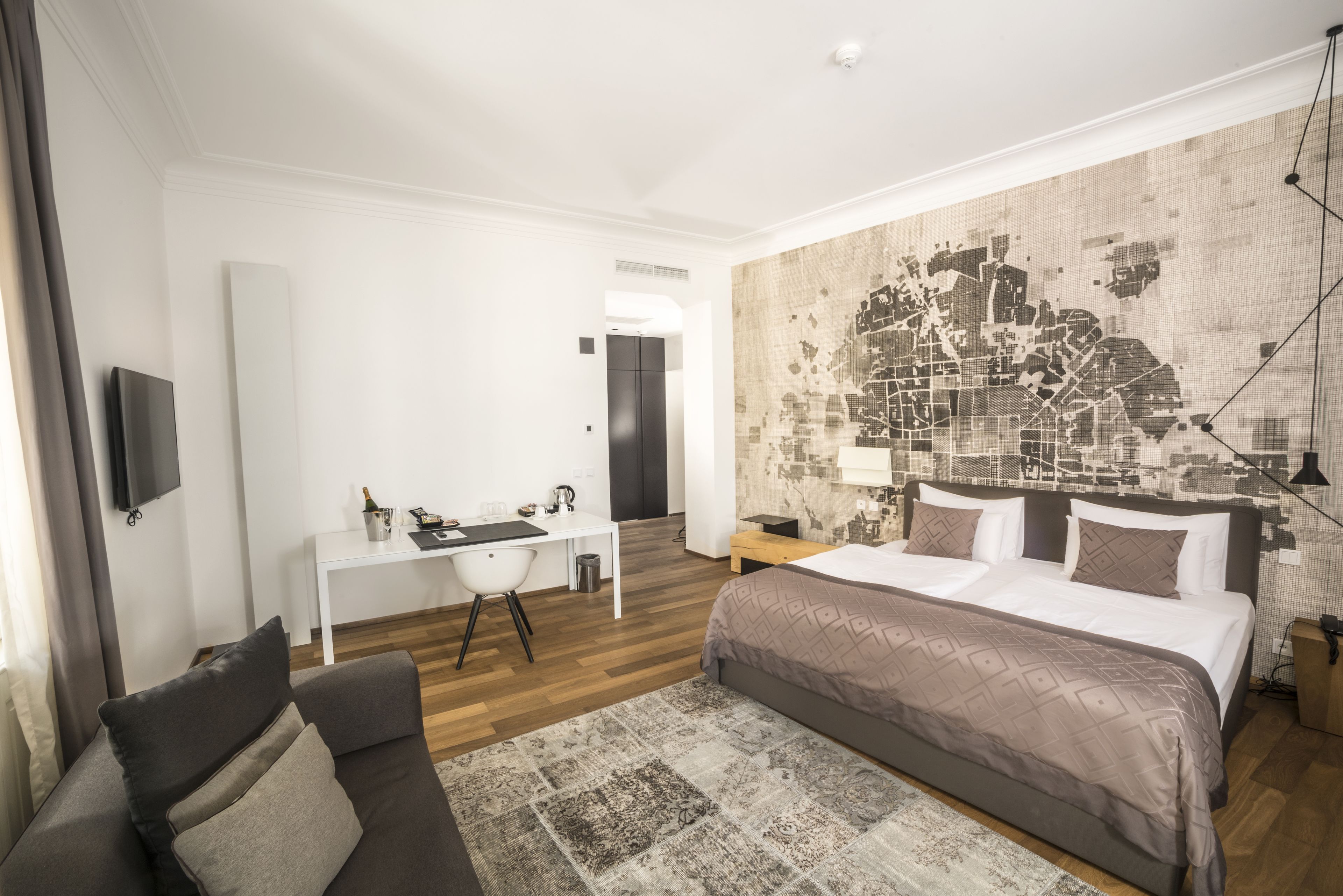 A modern hotel room with a large bed, a desk, and a seating area.