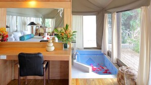 Ein Zimmer mit einem Holztisch, einem Stuhl, einem kleinen Pool mit Rosenblüten und Blick auf viel Grün.