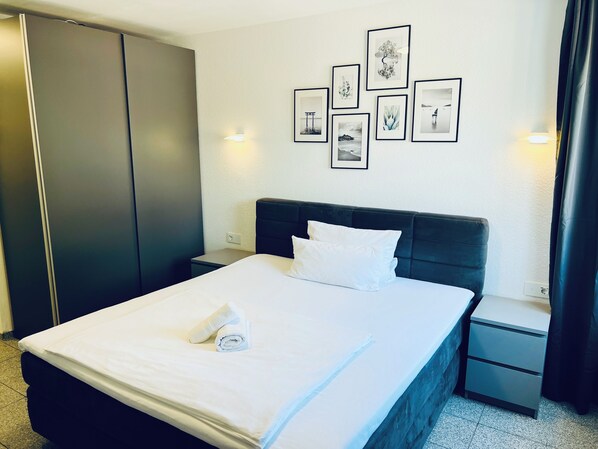 A hotel room with a bed, a nightstand, a wardrobe, and wall-mounted artwork.