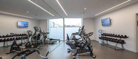 A modern gym with various exercise equipment, including treadmills, stationary bikes, and dumbbells.