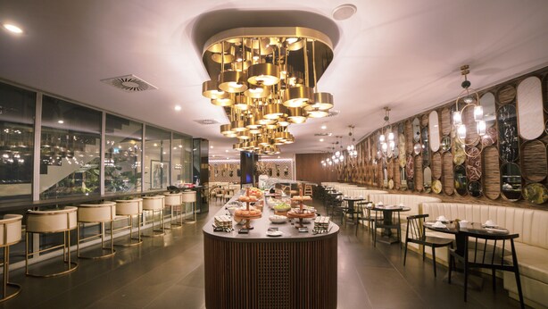 A modern restaurant with a central bar, seating area, and decorative wall mirrors. - BessaHotel Liberdade (Lisbon)