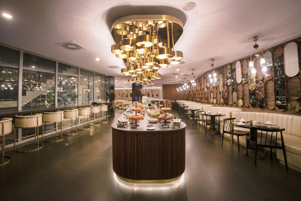Un restaurant moderne doté d’un bar central, d’un espace salon et de miroirs décoratifs sur les murs.