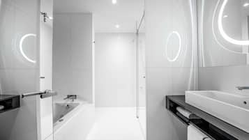 Un baño moderno con bañera, ducha y tocador con espejo.