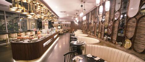 Un restaurant moderne doté d’un comptoir incurvé, de plusieurs espaces de restauration et de miroirs décoratifs sur les murs.