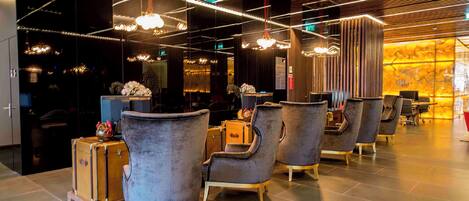 A modern interior with seating areas, pendant lighting, and a reflective wall.
