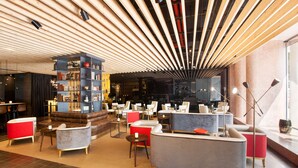 A modern lounge area with sofas, armchairs, and a bookshelf. - BessaHotel Liberdade (Lisbon)
