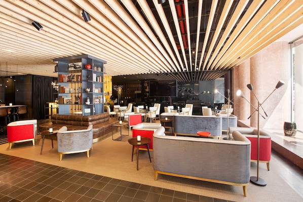 A modern lounge area with sofas, armchairs, and a bookshelf. - BessaHotel Liberdade (Lisbon)