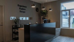 A reception area with a modern design, featuring a reception desk, a potted plant, and a wall with motivational text.