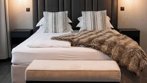 A modern bedroom with a large bed, two bedside tables, and a fluffy throw blanket.