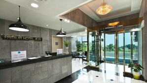 A hotel reception area with a modern design, featuring a reception desk, seating area, and a view of the outdoors. - Familia Hotel Jeju (Seogwipo)