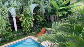 A pool surrounded by lush greenery and white columns. - Hotel Santa Ana (Mérida)