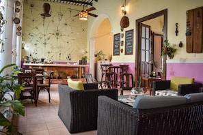 Un restaurant accueillant, doté de meubles en osier, d’un coin bar et de décorations murales originales.