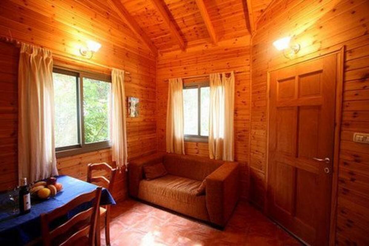 L’intérieur d’un chalet en bois, avec une table à manger, un canapé et une porte.
