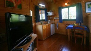 A wooden cabin interior with a TV, kitchenette, and dining area. - Amirim Atmosphere (Merom HaGalil)