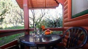 A wooden cabin with a glass table and chairs on a porch. - Amirim Atmosphere (Merom HaGalil)