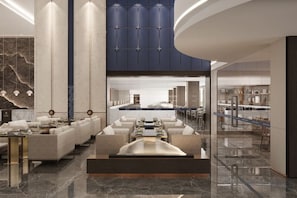 A modern hotel lobby with a central seating area, a kitchen visible through the glass, and a marble floor. - Blue Peninsula Hotel (Xiamen)