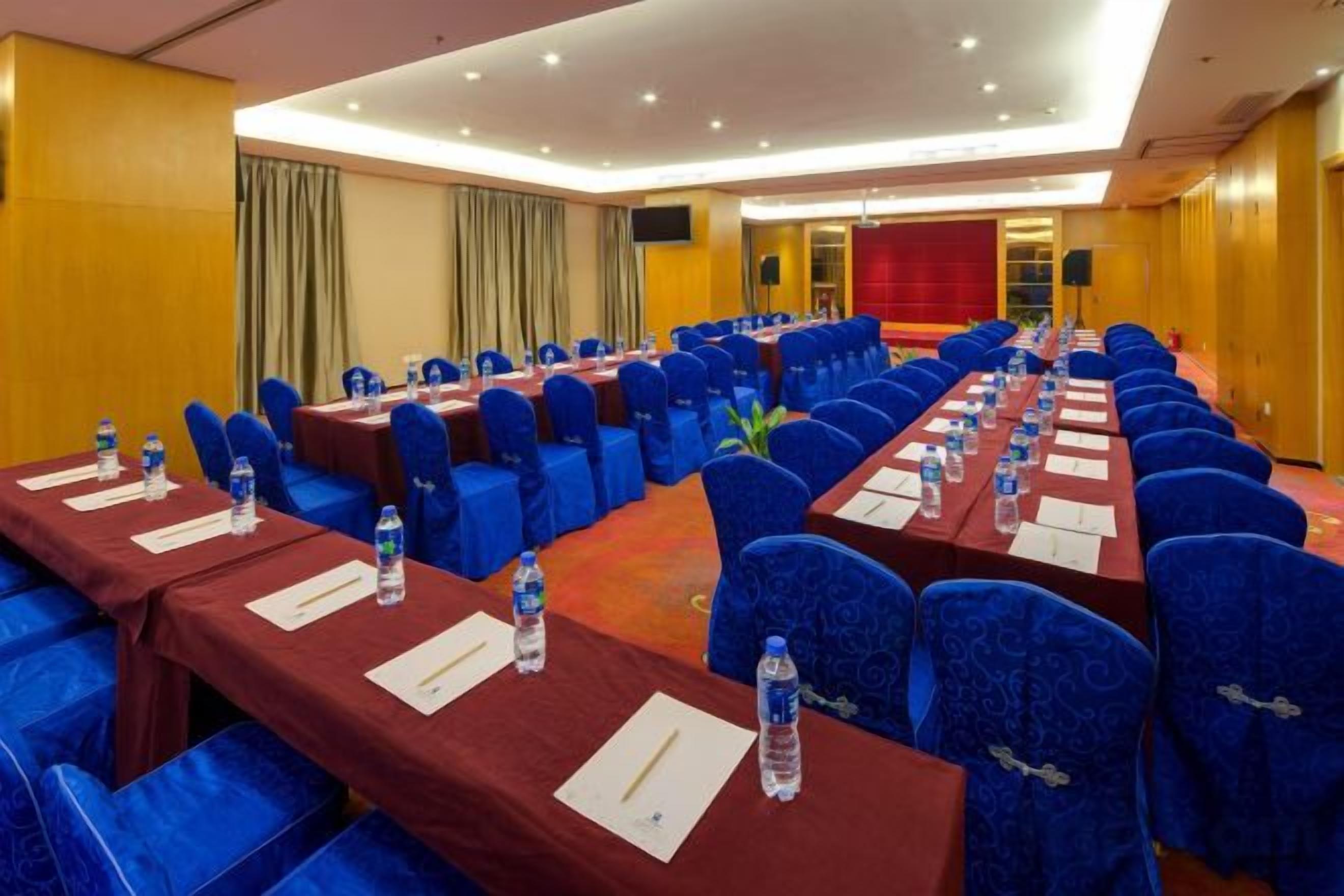 A conference room with rows of tables and chairs, equipped with water bottles and nameplates.