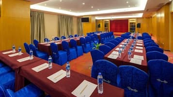 A conference room with rows of tables and chairs, equipped with water bottles and nameplates.