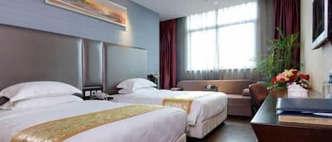 A hotel room with two beds, a sofa, a desk, and a large window with curtains.