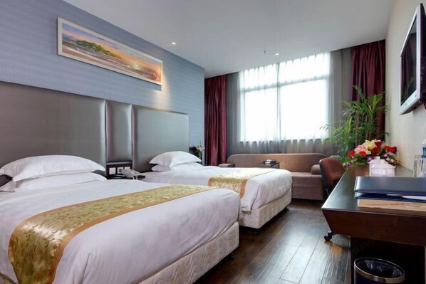 A hotel room with two beds, a sofa, a desk, and a large window with curtains. - Blue Peninsula Hotel (Xiamen)