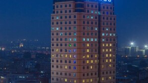 Un hotel moderno de gran altura con varias plantas, ventanas iluminadas y un letrero visible en la parte superior.