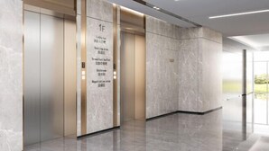 Un elevador moderno con pared de mármol y pantalla digital que detalla servicios como recepción, desayuno tipo buffet y baño.