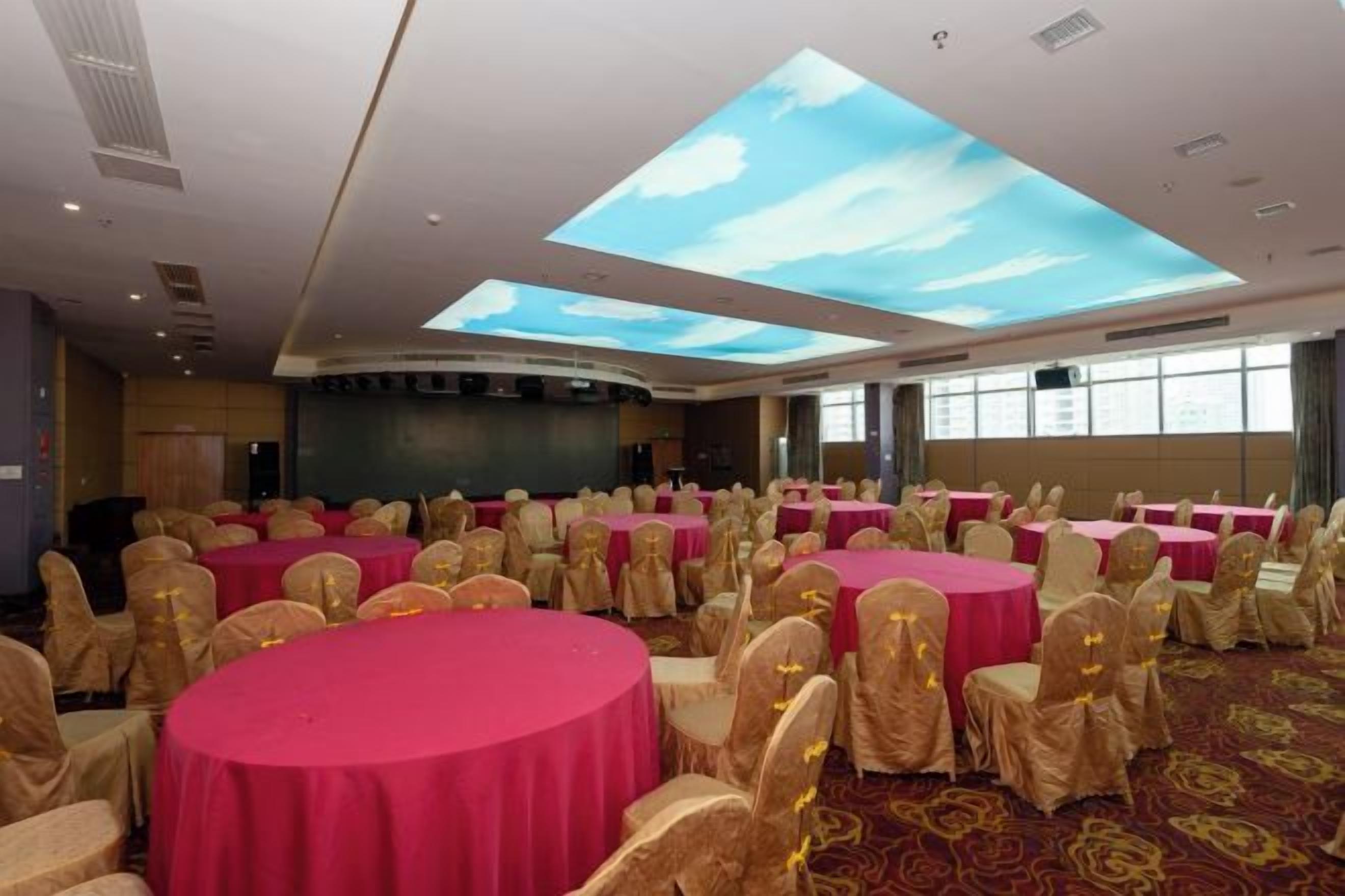 Une salle de conférence équipée de tables rondes, de chaises et d’un grand écran.