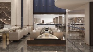 Un lobby moderno de hotel con un área de estar central, piso de mármol y vista al comedor.