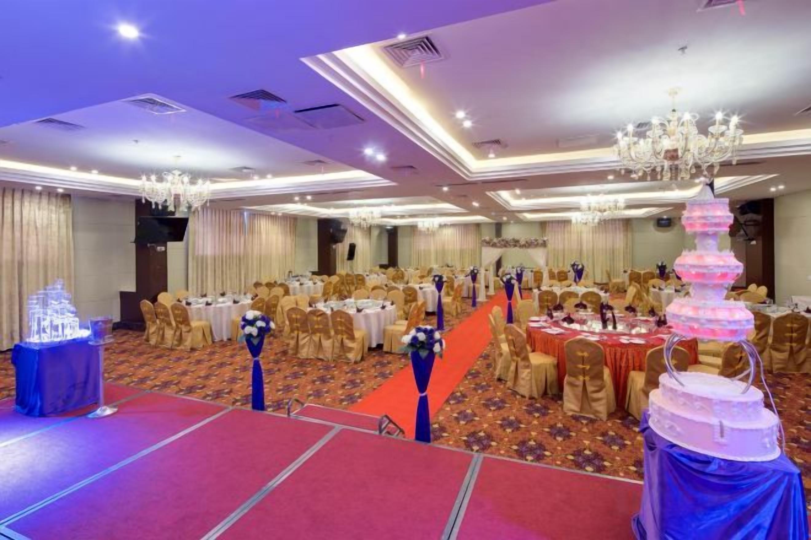 A banquet hall with round tables, chairs, and a stage area.