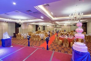 A banquet hall with round tables, chairs, and a stage area. - Blue Peninsula Hotel (Xiamen)