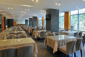 A spacious dining area with multiple tables and chairs, large windows, and a modern interior design. - Blue Peninsula Hotel (Xiamen)