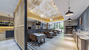 Un restaurante moderno con suelo a cuadros, mesas largas e iluminación colgante.