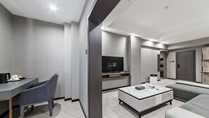 Una sala de estar moderna con un sofá gris, una mesita de centro y un televisor montado en la pared.