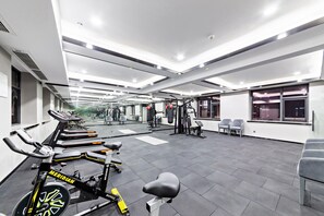 Un gimnasio con cintas de correr, bicicletas estáticas y máquinas de pesas.
