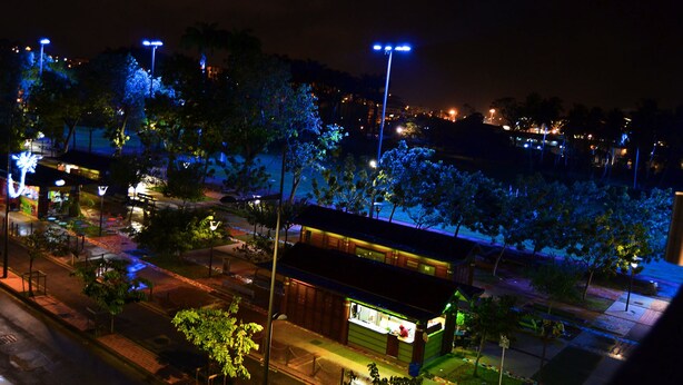 A nighttime view of a street with illuminated streetlights, trees, and a small building with a lit window. - Fort Savane (Fort-de-France)