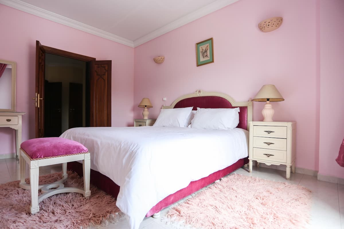 A bedroom with a bed, a nightstand, a dresser, a chair, and a door.