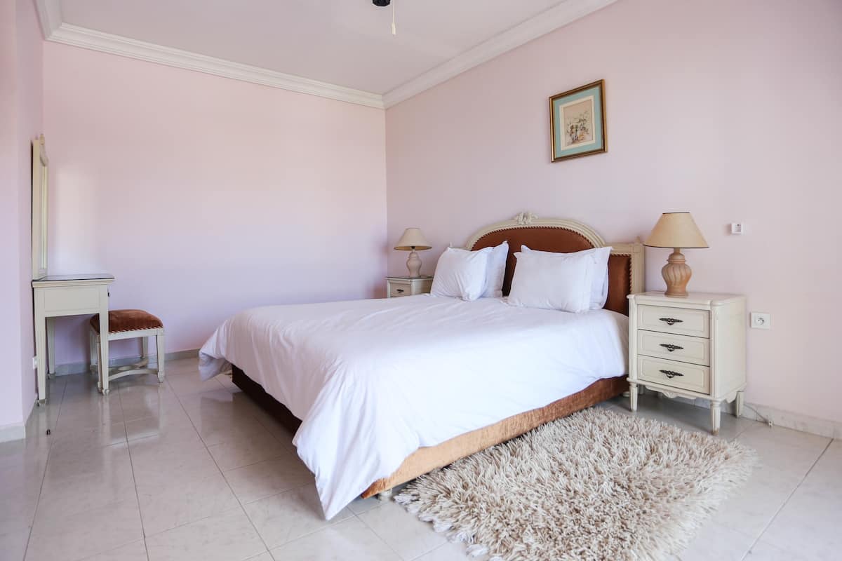 A bedroom with a bed, bedside tables, a mirror, and a rug.