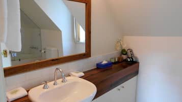 A bathroom with a white sink, wooden countertop, and a large mirror.