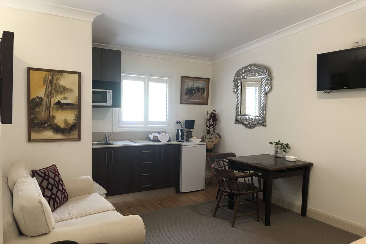 A compact living space with a kitchenette, a dining area, and a seating area with a sofa and a table.