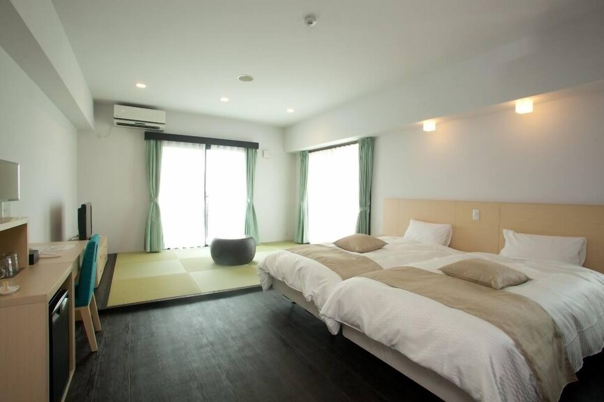 A modern hotel room with a large bed, a desk, and a seating area.