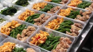 Ein Buffet mit verschiedenen Speisen, darunter Reis, grüne Bohnen, Rührei und Fleischgerichte.