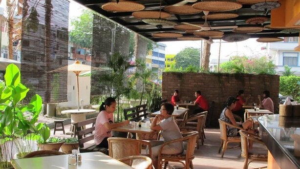 Ein Straßencafé mit Korbmöbeln und einer Ziegelwand im Hintergrund.