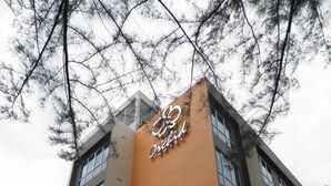 Ein Hotel mit einem auffälligen, vertikalen, orangefarbenen Schild, auf dem 'The Orchid Hotel' steht.