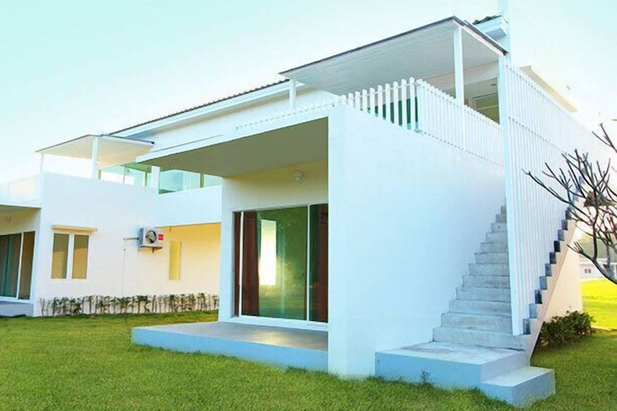 A modern two-story house with a flat roof, large windows, and a staircase leading to an upper level.