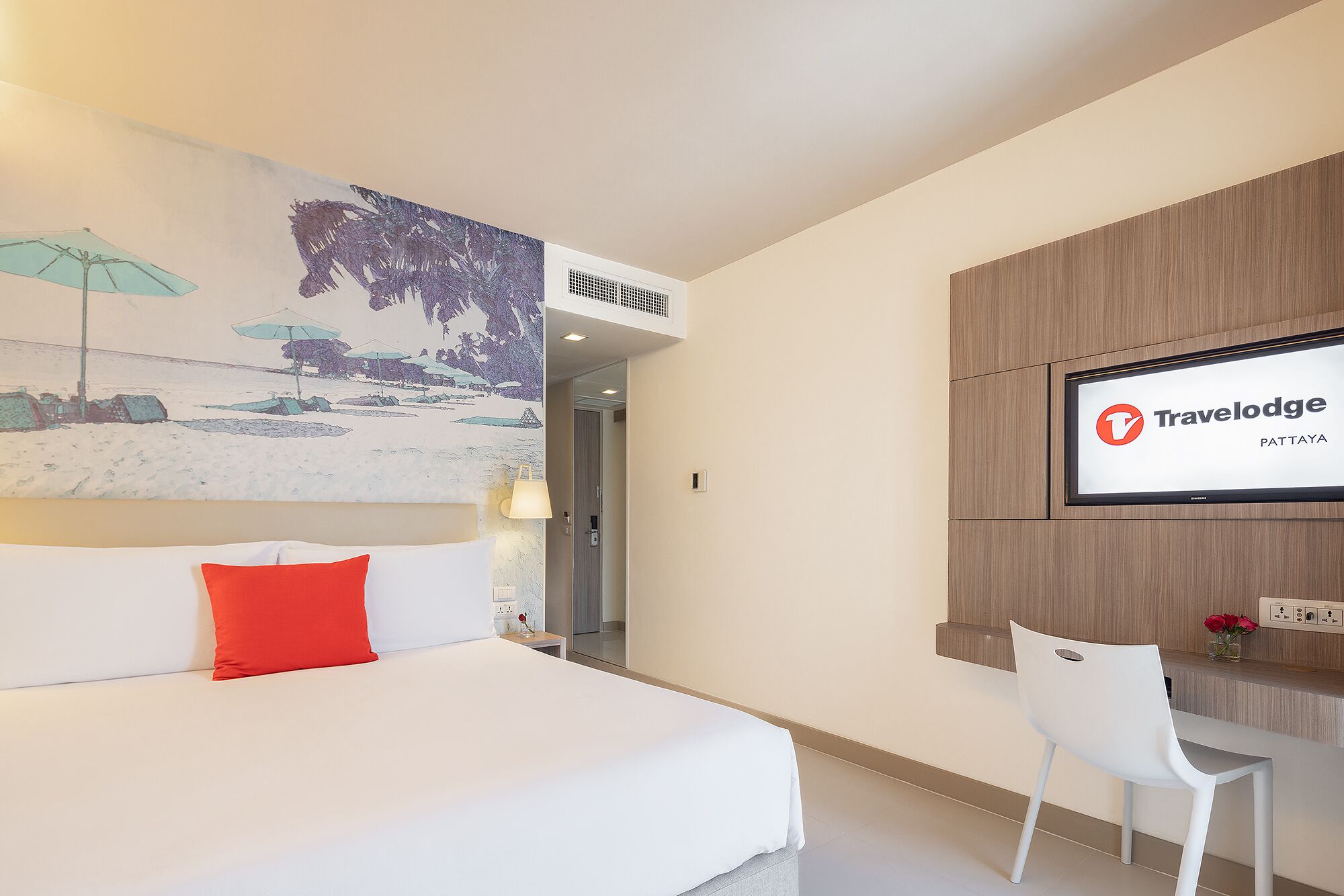 A hotel room with a bed, a desk, a TV, and a mural.