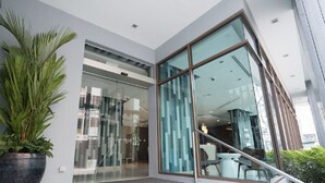 A modern building entrance with a glass door, a potted plant, and a staircase leading inside. - Travelodge Pattaya (Pattaya)