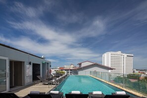 Una piscina al aire libre, sillones reclinables de piscina